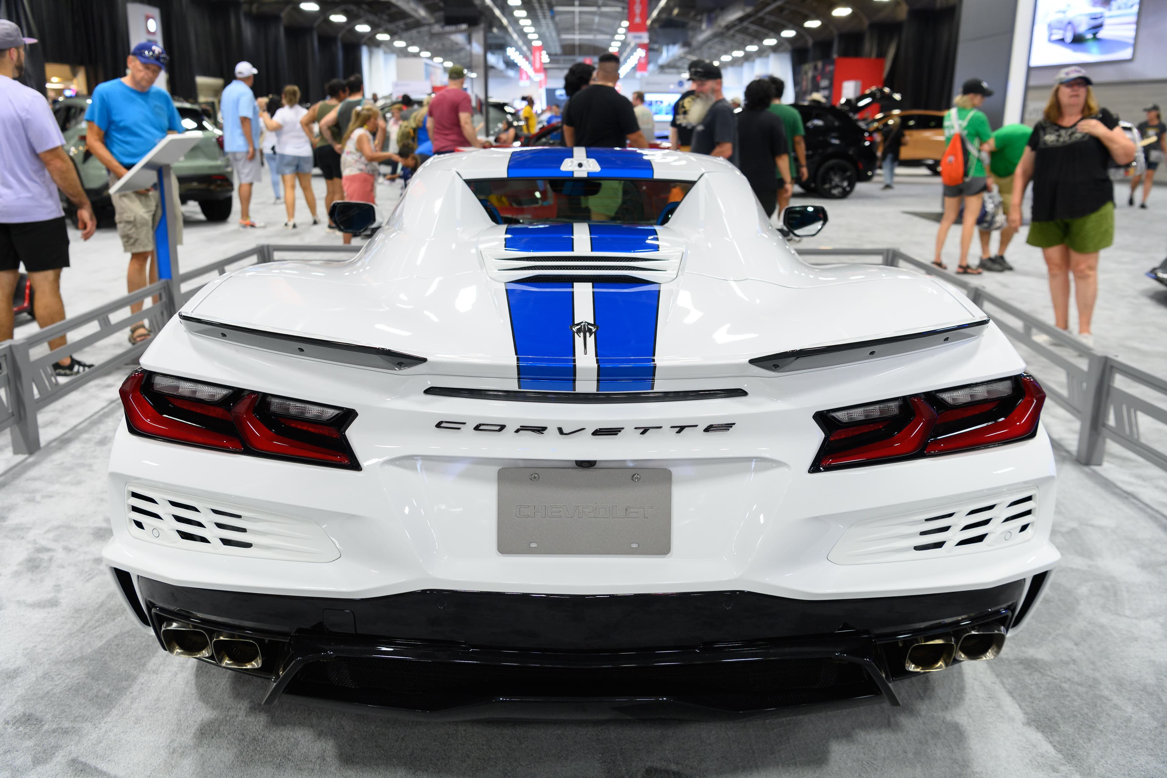 File photo: Visitors view a white sports car with blue stripes at an indoor vehicle display in 2023.