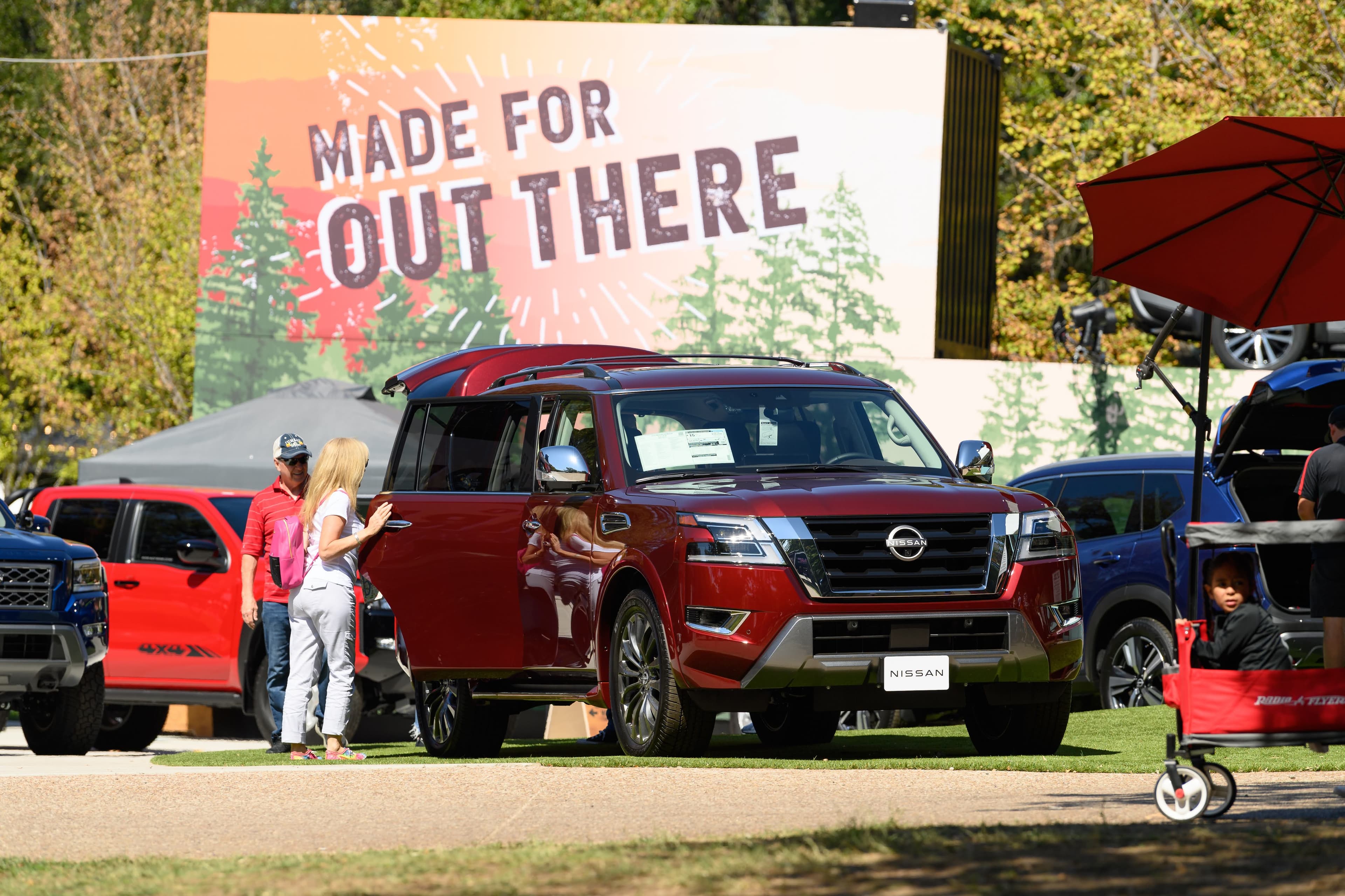 File photo: Visitors stand near a red SUV at an outdoor vehicle display in 2023.